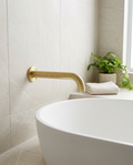 Aurea Brushed Brass Wall Mounted Bath Spout in a bright modern bathroom