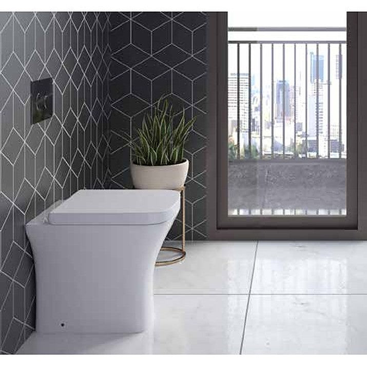Outlyne close coupled toilet in a modern bathroom with a dark tiled wall